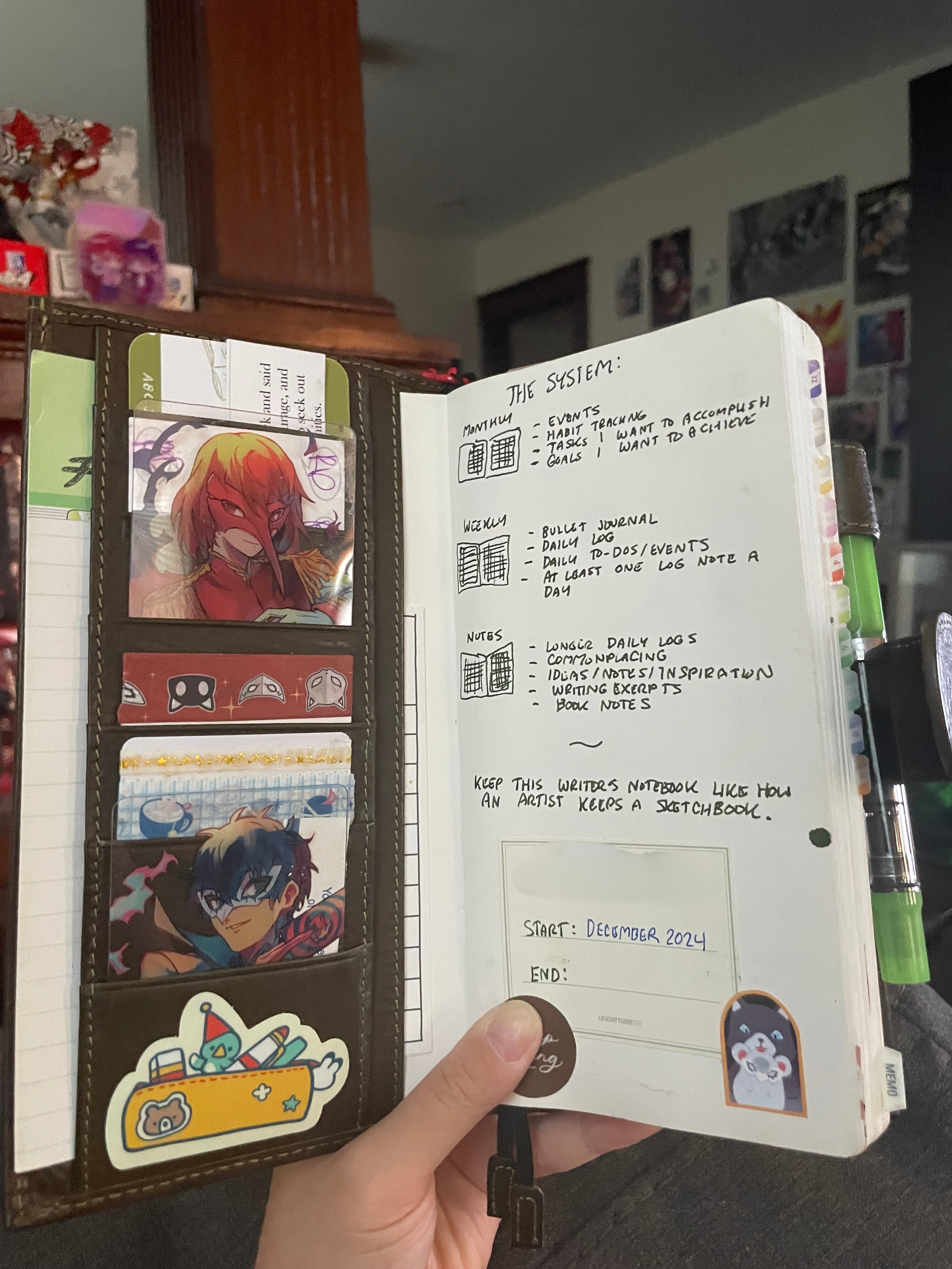 the inner cover. on the left are several card slots, filled with washi tape cards and akeshu photocards. a half-used packet of midori numbered index tabs is tucked in the left pocket. the right shows a page explaining my system: 'monthly pages: events, habit tracking, tasks i want to accomplish, goals i want to achieve. weekly pages: in a weekly horizontal layout with a blank grid page on every right page, bullet journal, daily log, daily to-dos/events, write at least one log note a day. notes section: for longer daily logs, commonplacing, ideas/notes/inspiration, writing excerpts. a label is attached with two spaces to put down the start and end date of this planner.