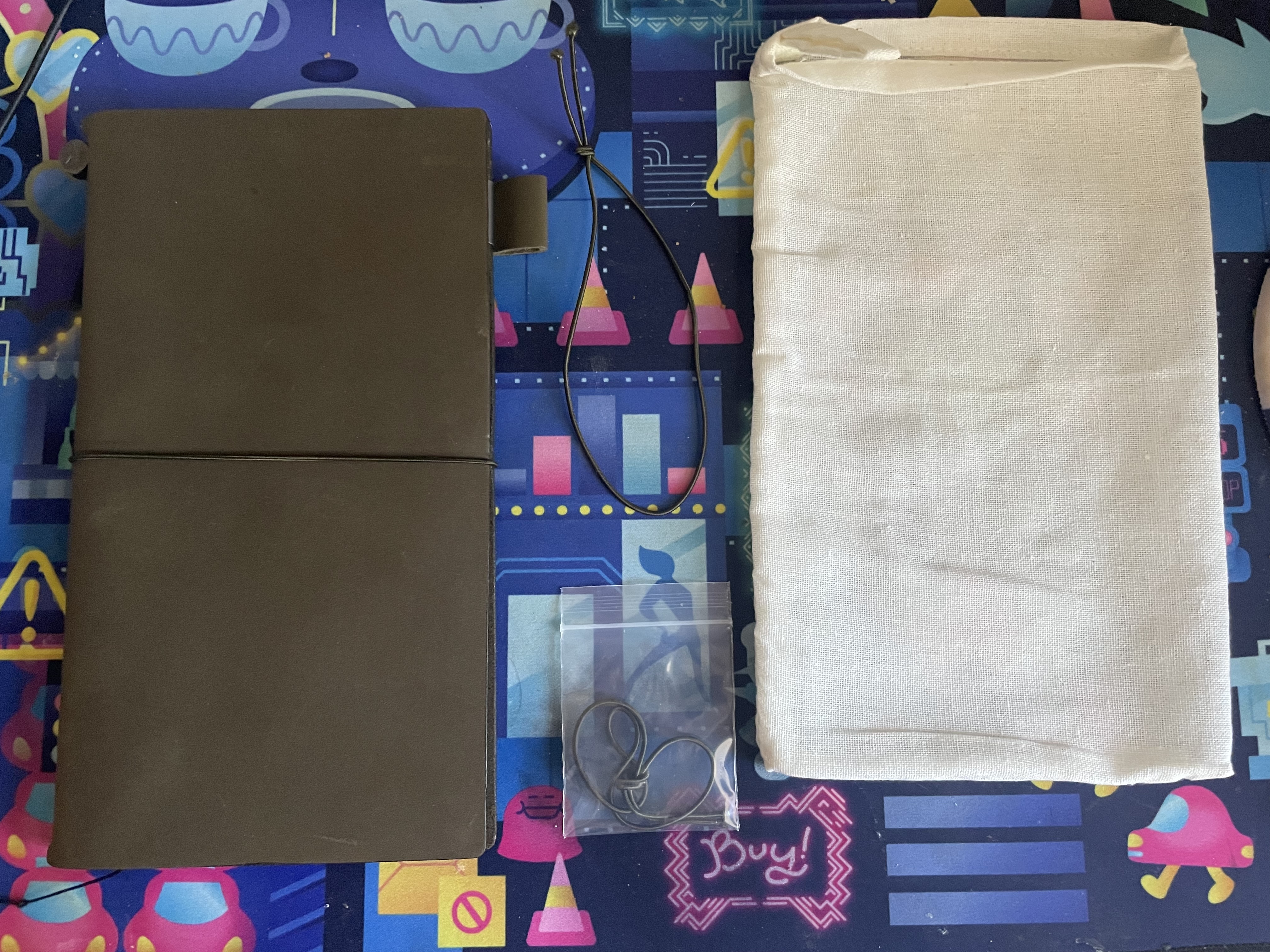 the contents of the olive traveler's notebook package: the notebook cover, a spare elastic, a cotton bag, and an additional elastic that kept the package together